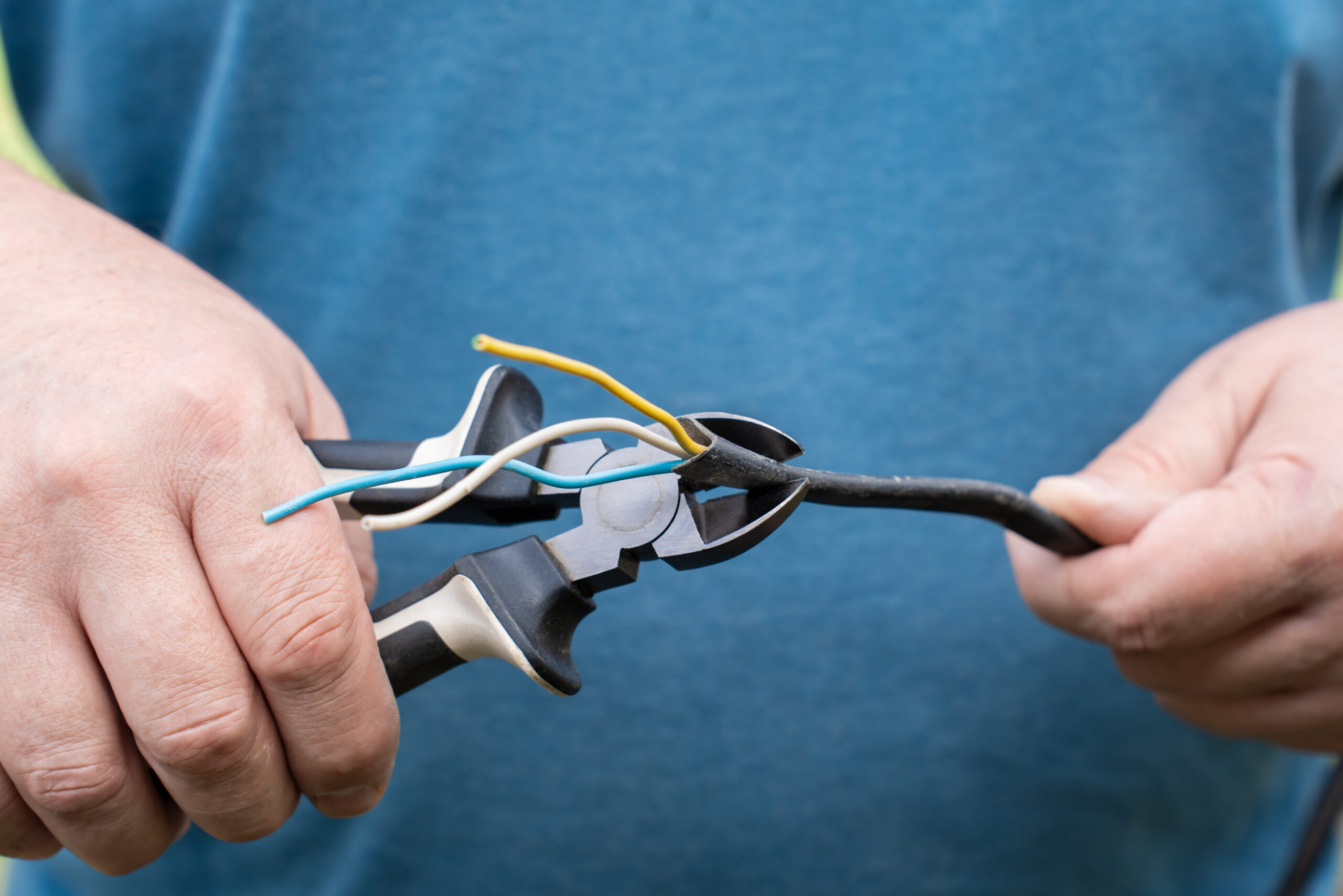 Carefully Cutting and Stripping Electrical Wires with Nippers in a Home Repair Project Carefully Cutting and Stripping Electrical Wires with Nippers in a Home Repair Project