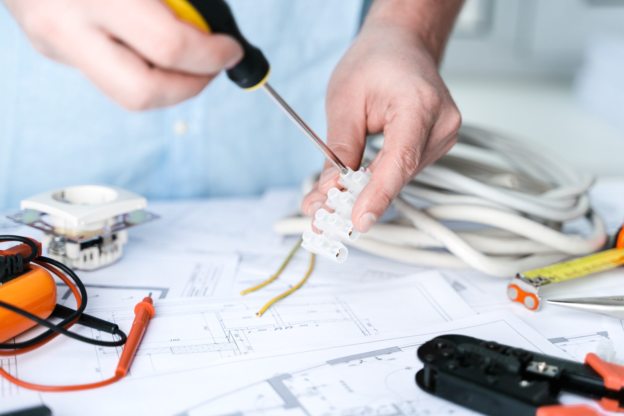 Man,repairer making electricity project in house.Repairs planning.Drawings,diagrams,plan for electrification of apartment,building.Devices,accessories,voltmeter,wires,screwdriver,pliers,tape measure